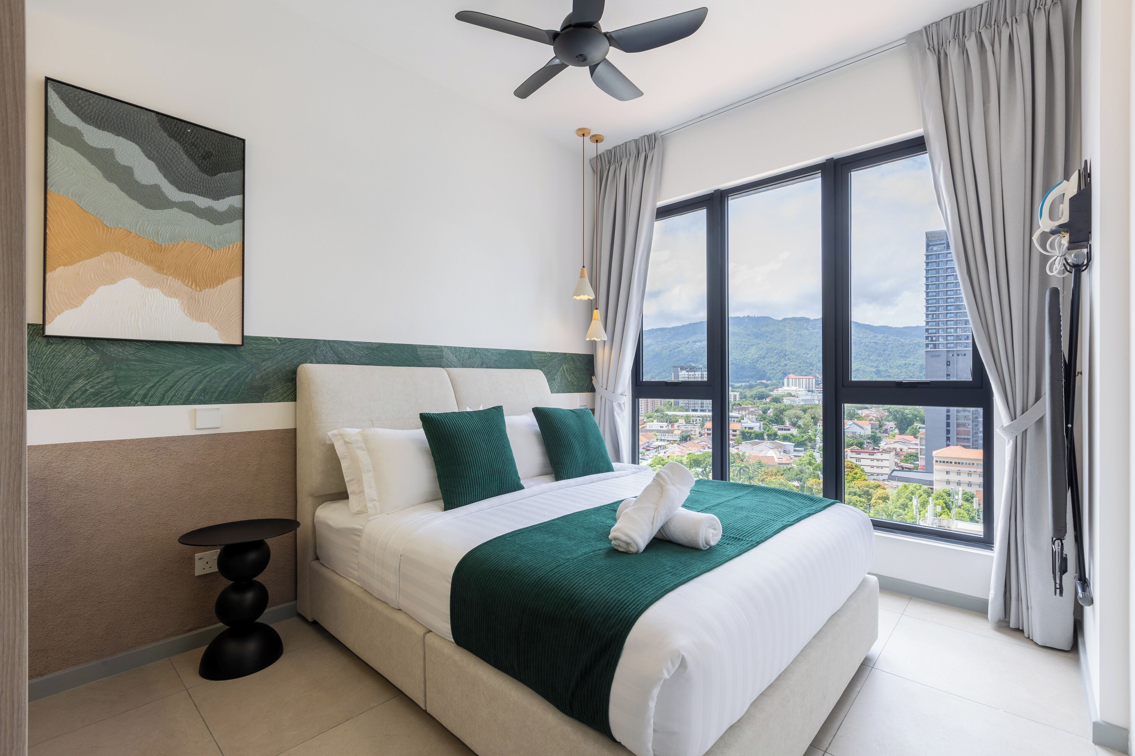 Une chambre d’hôtel moderne avec un grand lit, une vue sur la ville et un ventilateur de plafond.