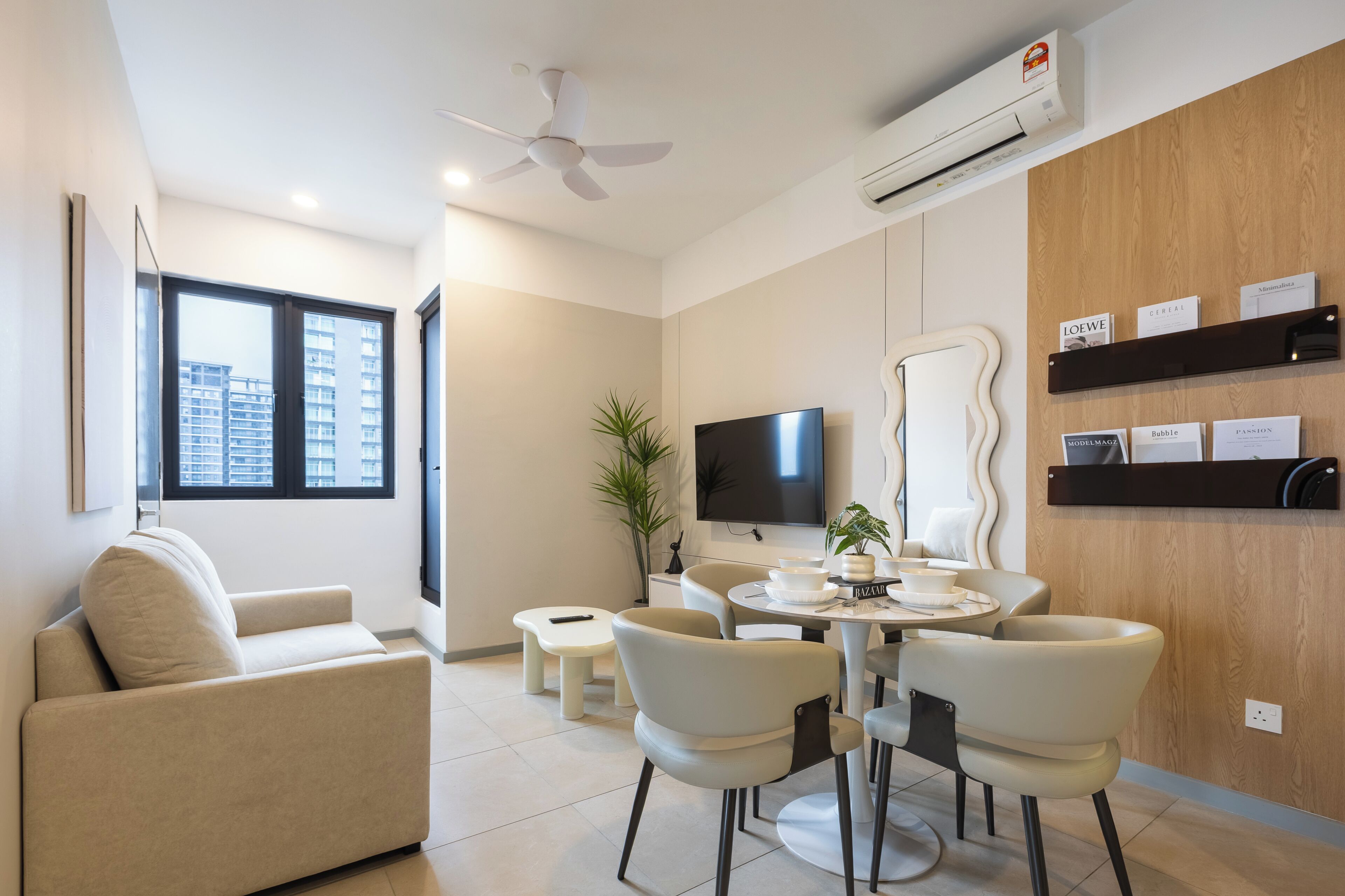 A modern living room with a sofa, dining table, chairs, a TV, and a wooden wall with shelves.