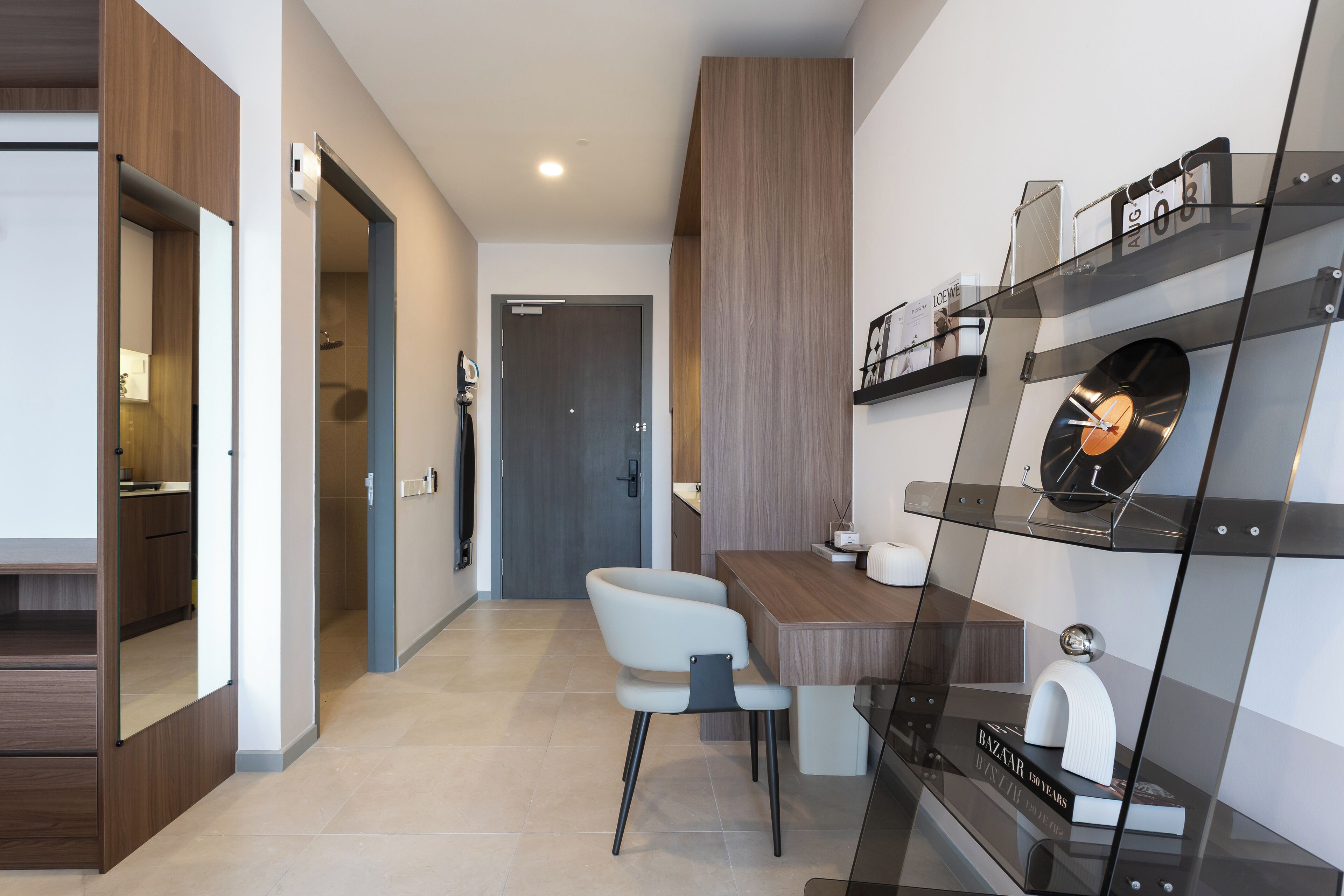 Une cuisine moderne avec un plan de travail en bois, une chaise blanche et une étagère en verre ornée d’objets décoratifs.