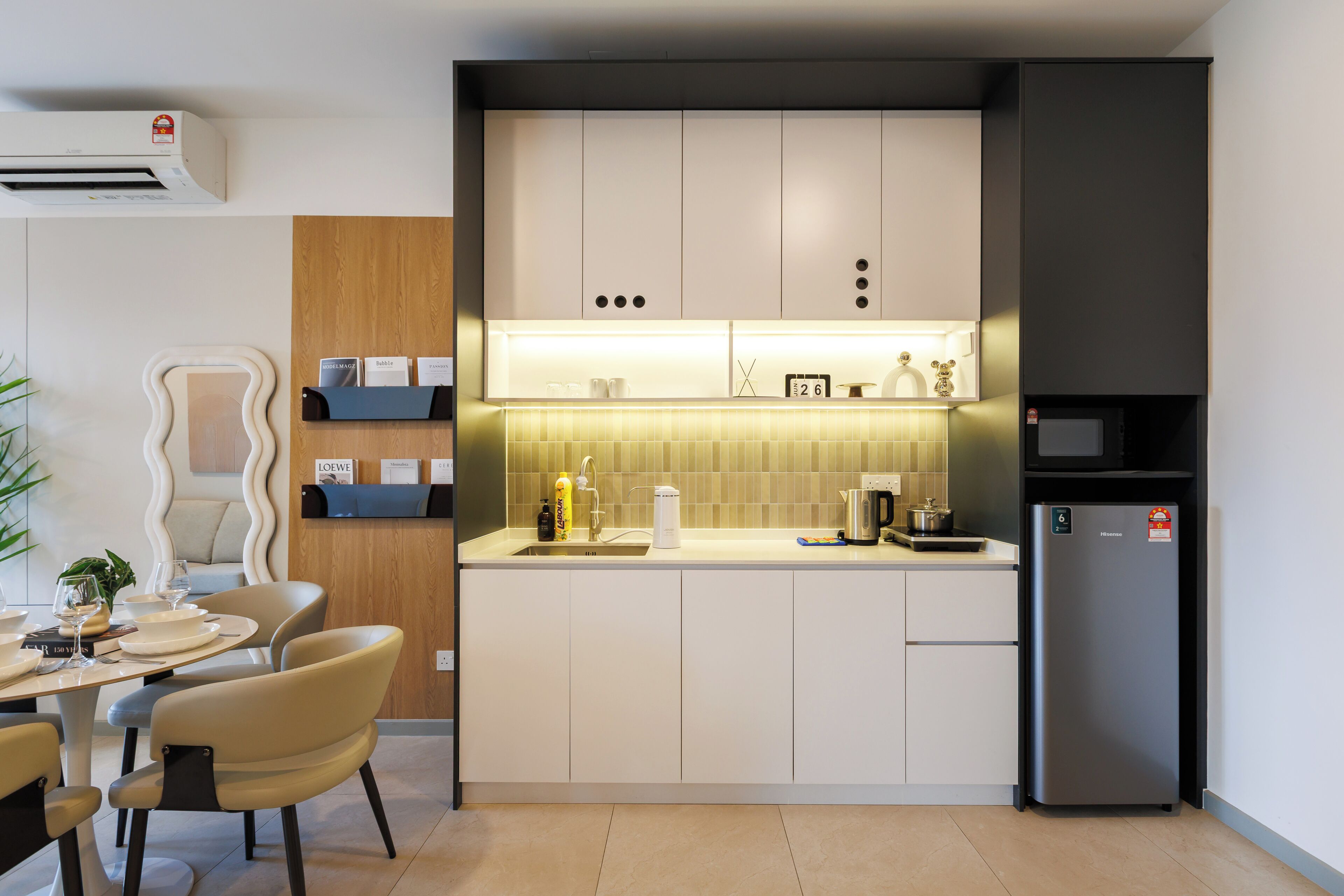 A modern kitchen with a built-in microwave, a refrigerator, and a dining area with a table and chairs.