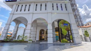 A modern building with a white facade, large arched entrances, and a sign for 'Exsim Macalisterz'. - 22 Macalisterz (George Town)