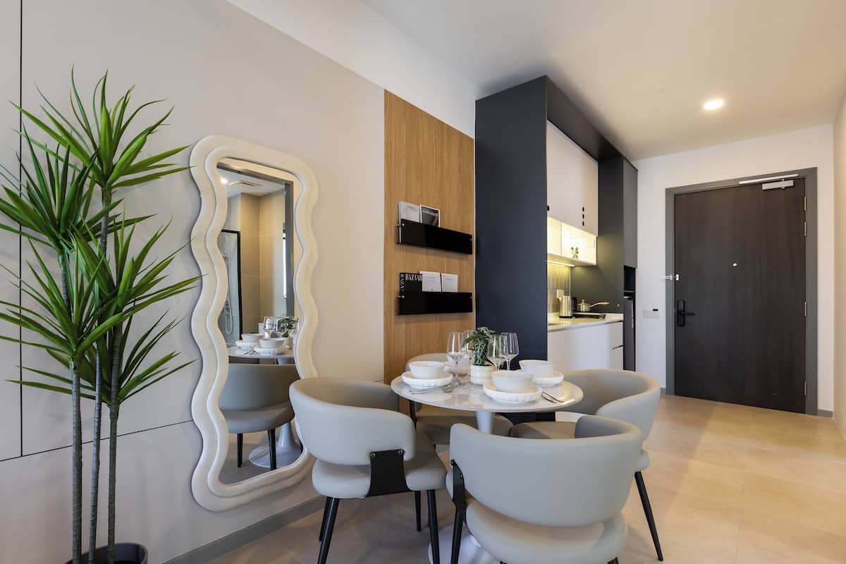 A modern dining area with a round table, grey chairs, and a decorative mirror.