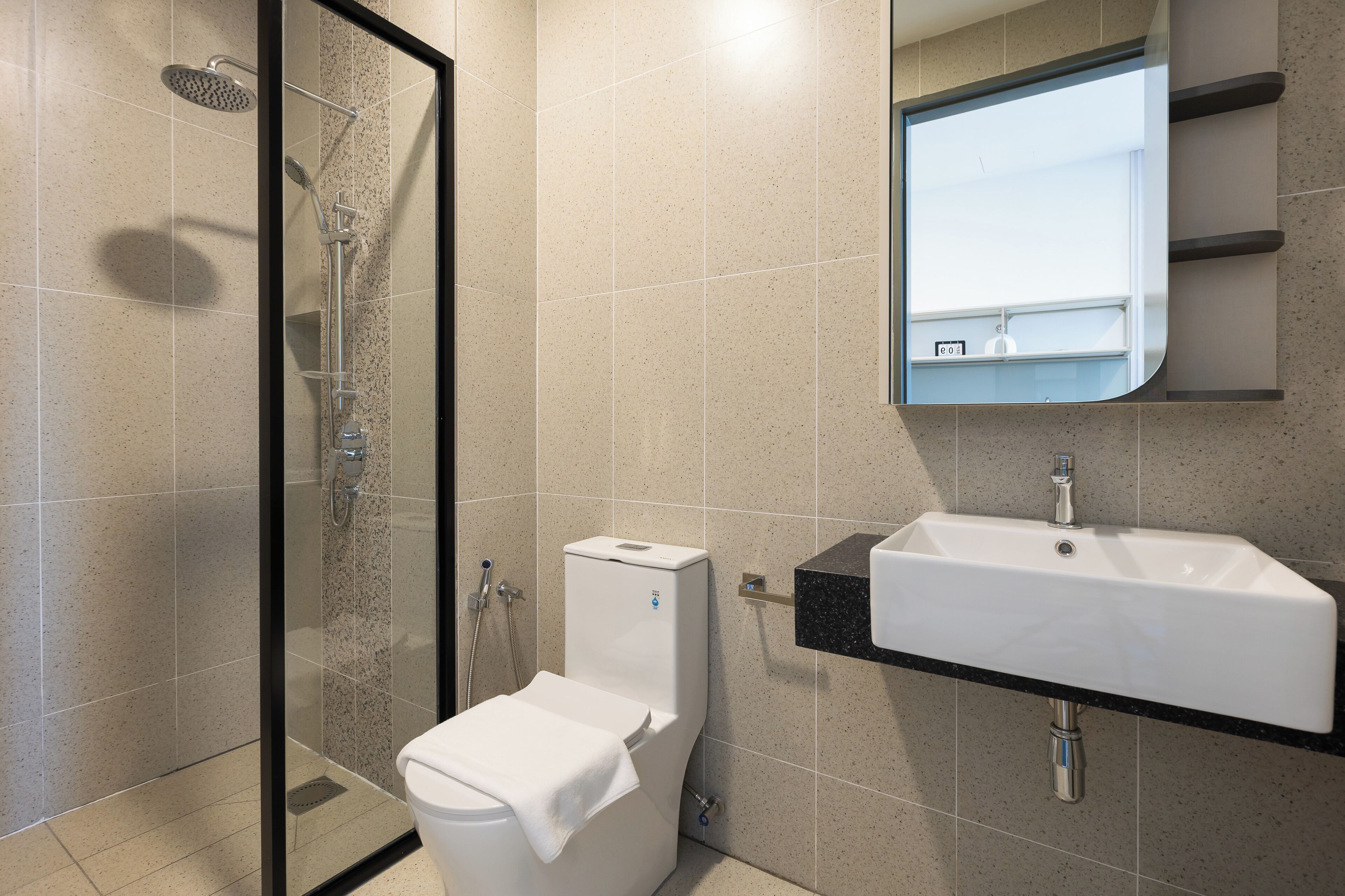 Un baño moderno con ducha envuelta en vidrio, inodoro y lavabo con espejo.