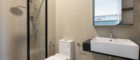A modern bathroom with a glass-enclosed shower, a toilet, and a sink with a mirror above it.