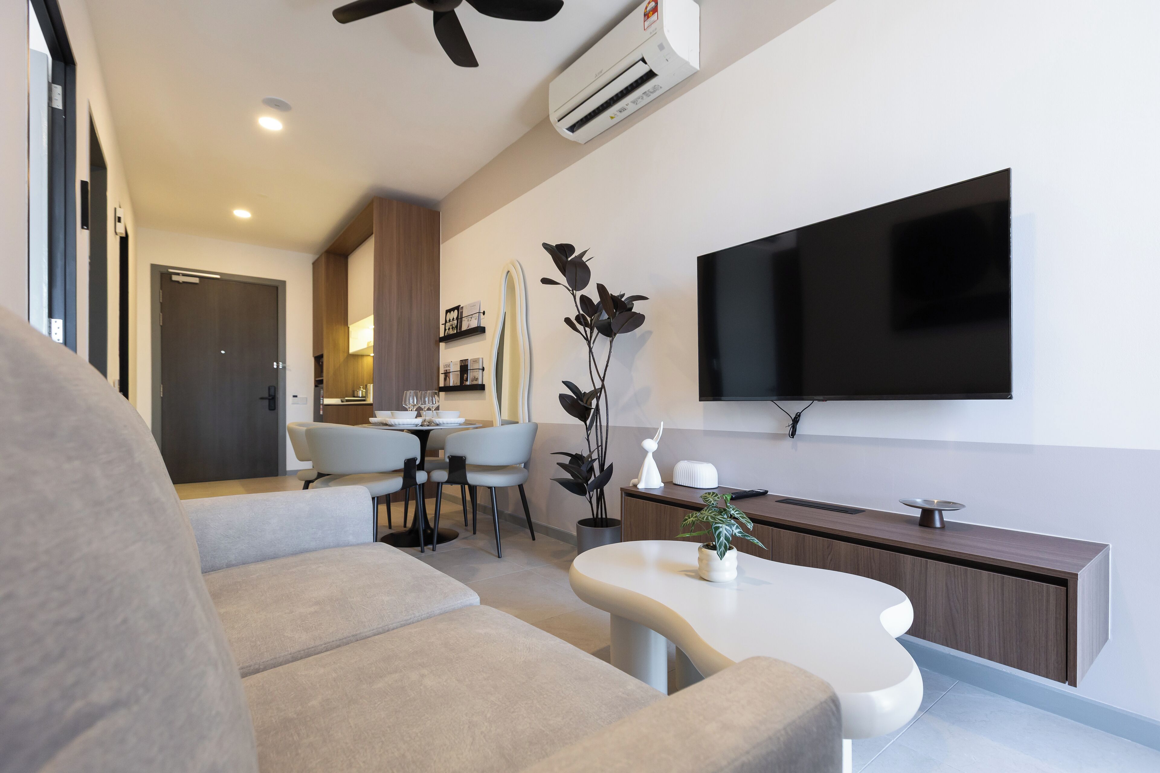 Un salon moderne avec un canapé, une table basse et un téléviseur à écran plat fixé au mur.