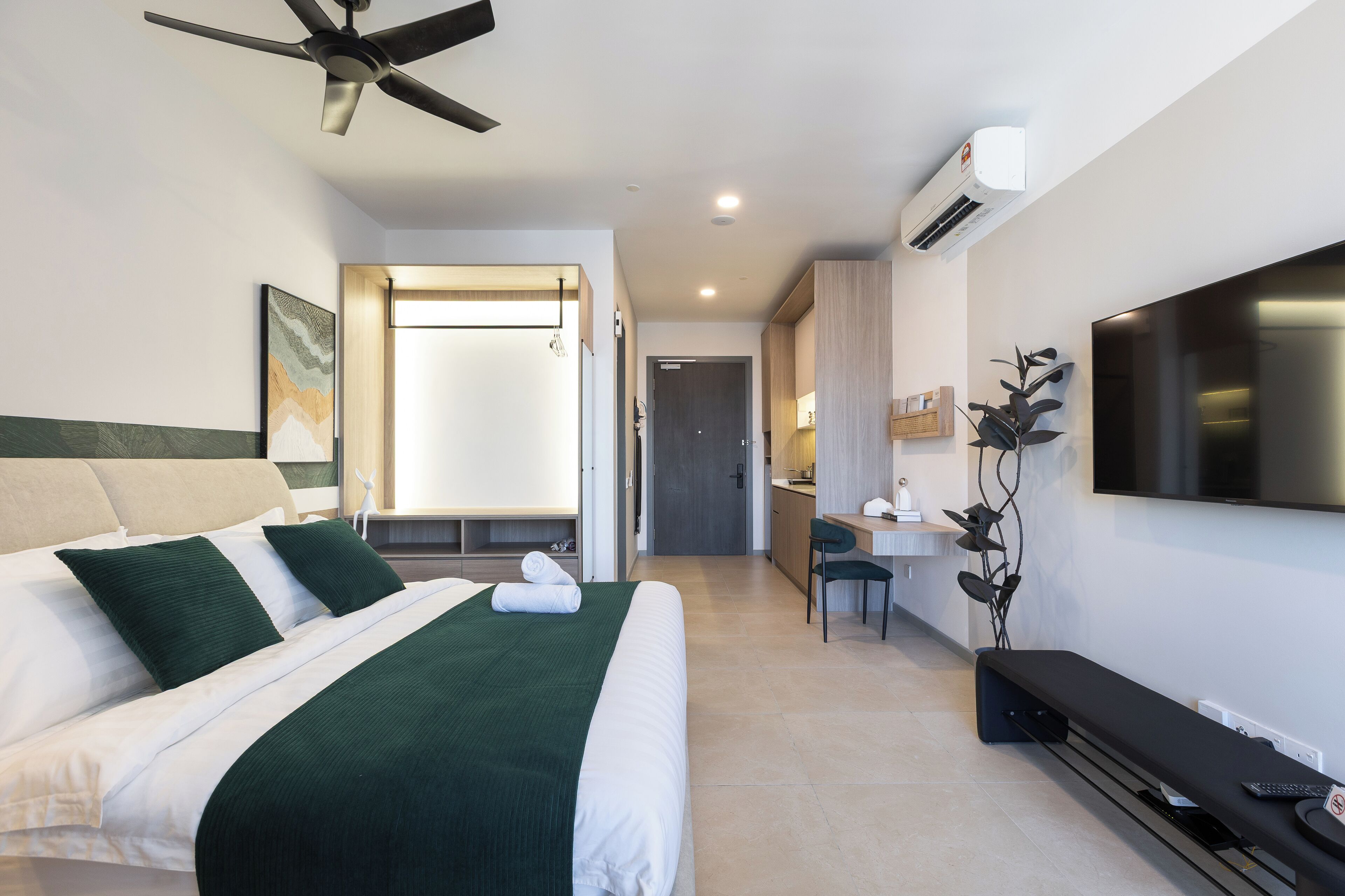 A modern hotel room with a bed, a desk, a chair, a TV, and a ceiling fan.