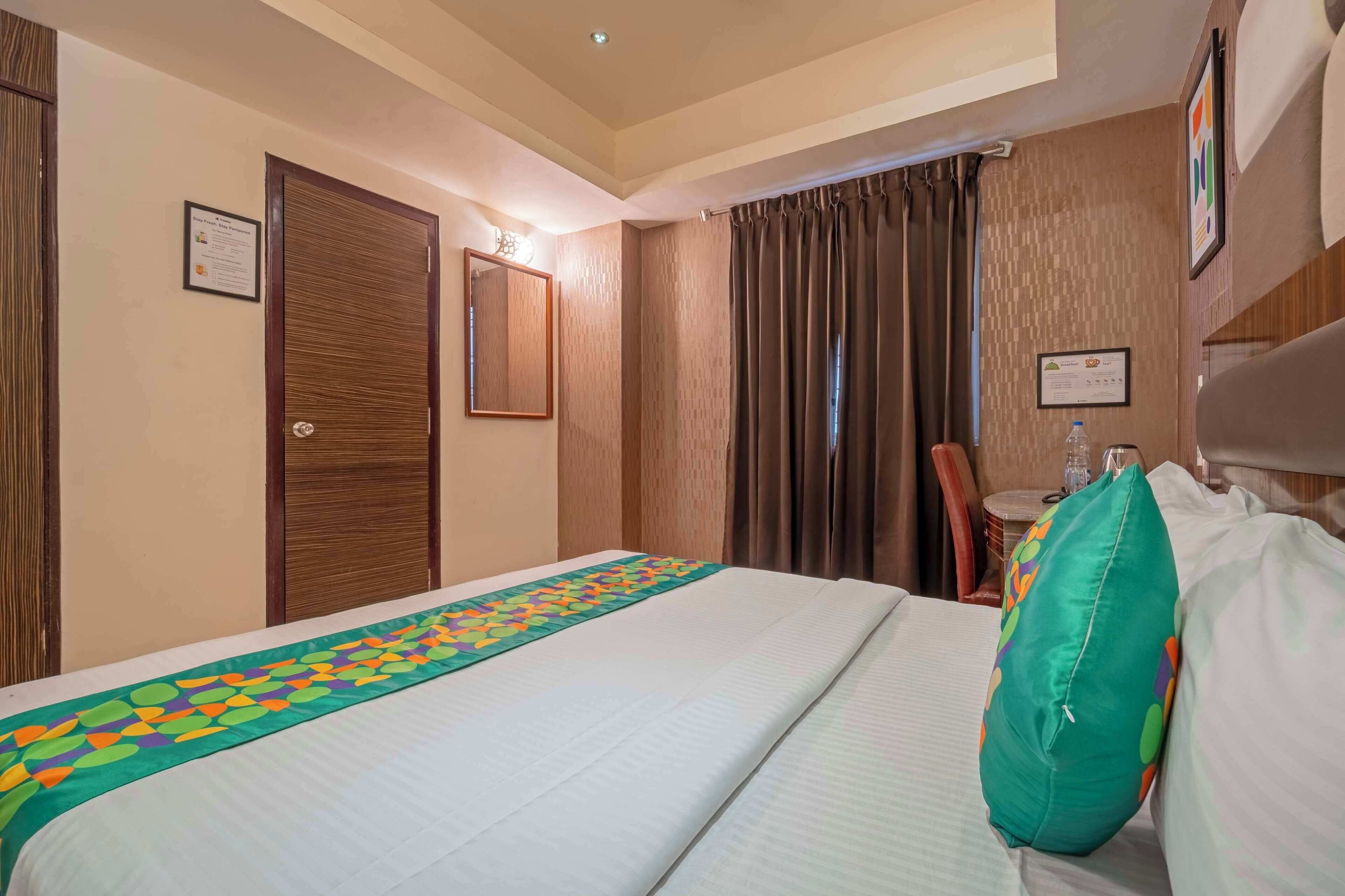 Une chambre d’hôtel avec un lit, un bureau, une chaise et une fenêtre avec des rideaux.