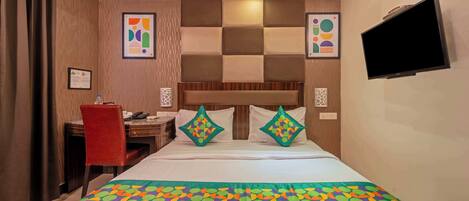 A hotel room with a bed, a desk, a chair, a television, and artwork on the walls.