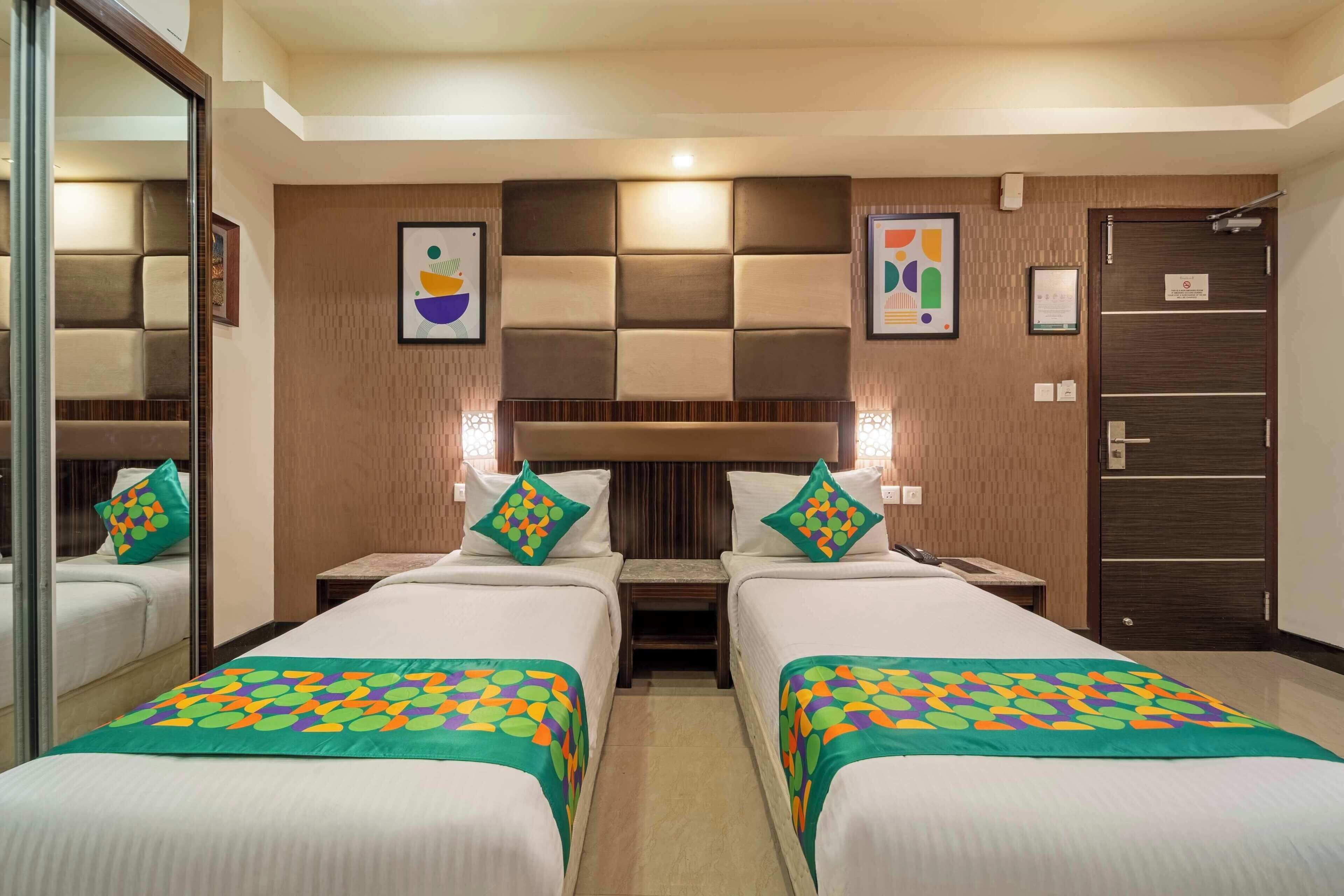 Habitación de hotel con dos camas, un espejo grande, cabecero de madera y obras de arte en las paredes.