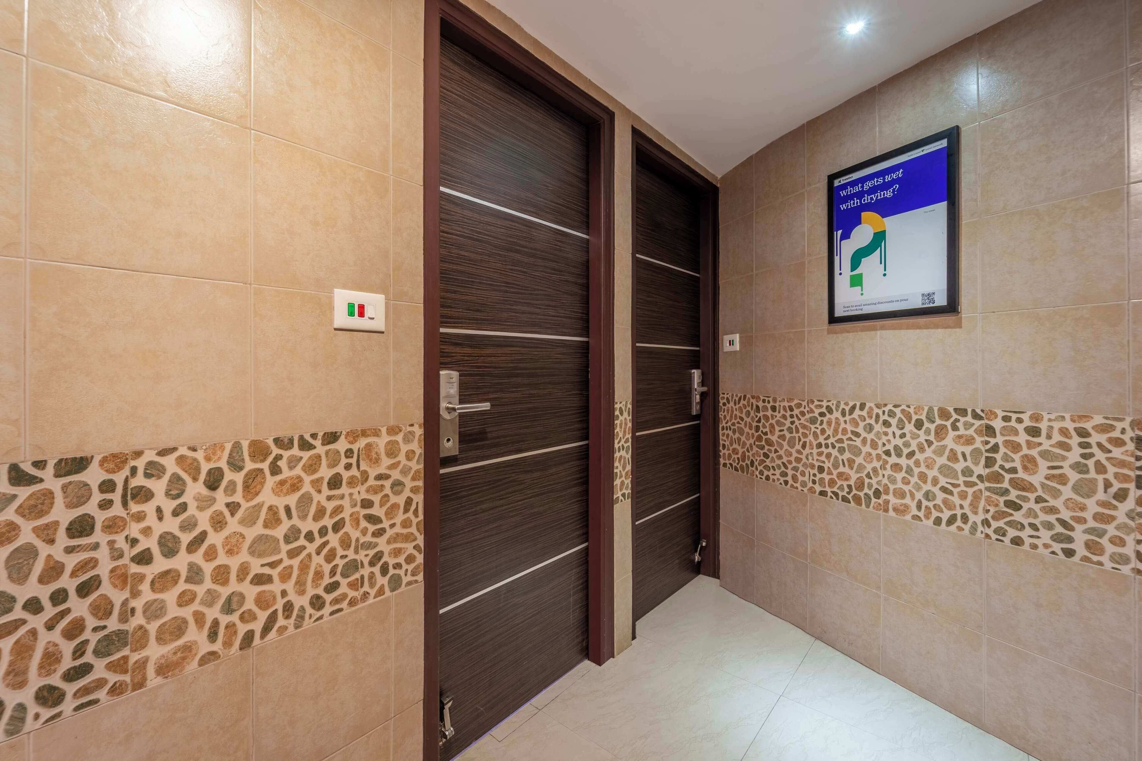 A hallway with tiled walls, a door with a wooden frame, and a poster on the wall.