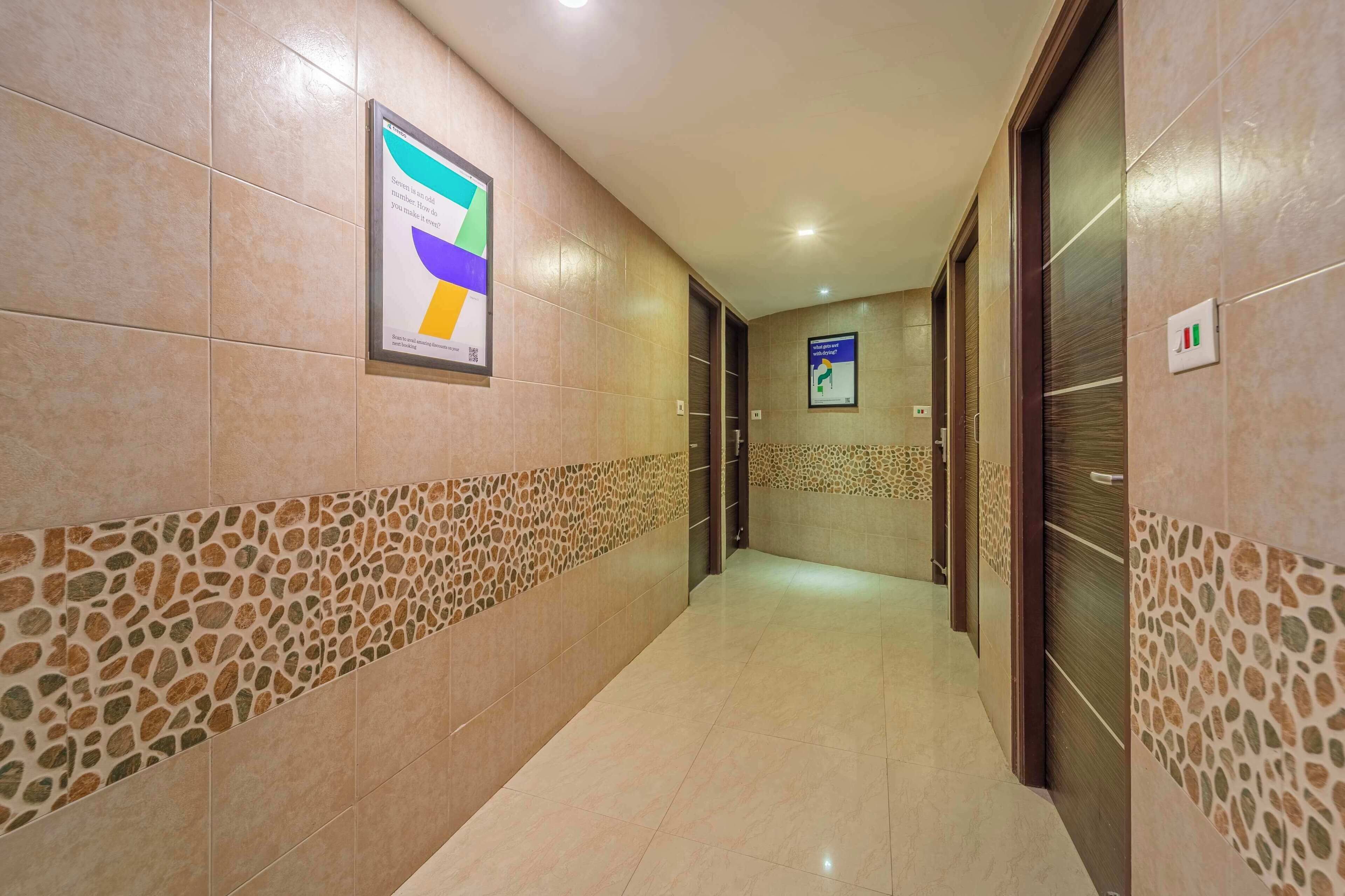 Un pasillo con paredes de azulejos, una pared decorativa con diseño y un cartel a la izquierda.