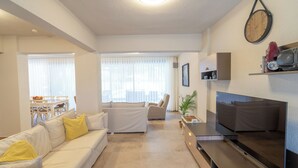 A modern living room with a sofa, TV, and a dining area with a table and chairs. - Jessic Villas (Hisarönü)