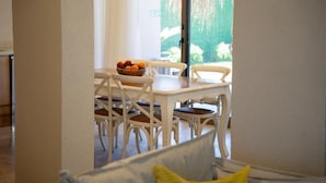 A dining area with a table and chairs, a bowl of fruit on the table, and a view of greenery outside. - Jessic Villas (Hisarönü)