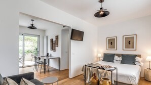 Et moderne hotelværelse med seng, sofa, spiseplads og fjernsyn på væggen.