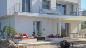 A modern two-story building with a balcony, outdoor seating area, and a view of the surrounding landscape. - Ginepro - Shelter by the sea in Apulia | A few steps from the beach (Puglia)