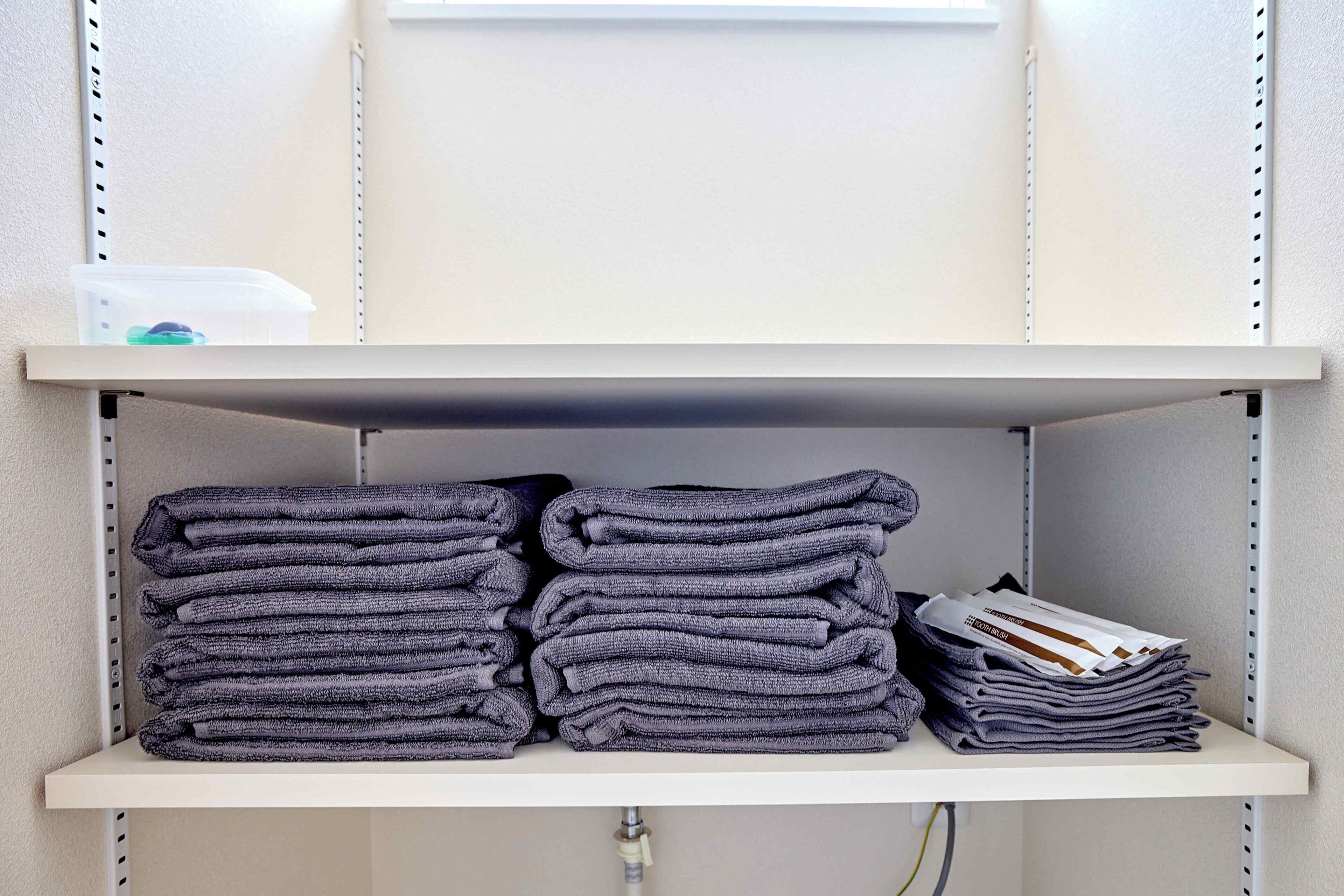 A shelf with folded towels and a stack of magazines.