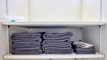 A shelf with folded towels and a stack of magazines.