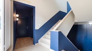 Una escalera moderna con detalles azules y blancos que conduce a una puerta con la leyenda 'Suites/Flats V 1.1'.