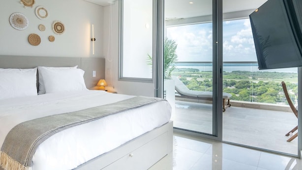 Un dormitorio moderno con una cama grande, un balcón con vistas y decoración en la pared.