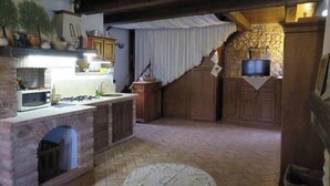 Une cuisine rustique avec un mur en pierre, des armoires en bois, un four à micro-ondes encastré et une cheminée.