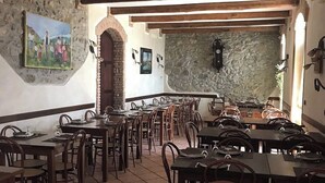 Un restaurant aux murs de pierre, aux tables et aux chaises en bois.