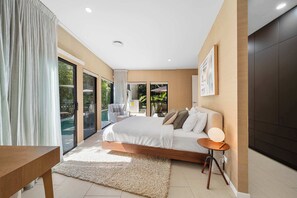 Un dormitorio moderno con una cama grande, una mesita de noche y vistas a una piscina.
