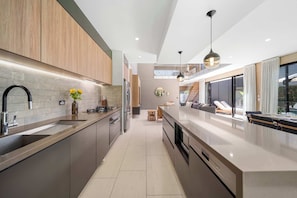 Una cocina moderna con una isla central, electrodomésticos de acero inoxidable y vistas a un balcón.