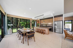 Uma cozinha moderna com uma ilha central, eletrodomésticos de aço inoxidável e uma área de jantar com uma mesa grande e cadeiras.