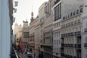 A street view with historic buildings, including a prominent statue and ornate architecture. - LUTHIA Puerta del Sol (Madrid)