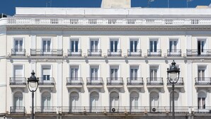 Un edificio de varios pisos con fachadas blancas, varios balcones y un farol.
