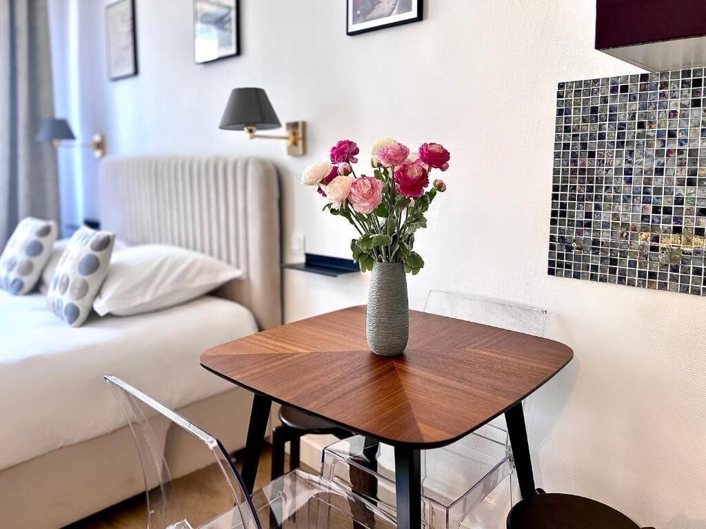 A modern living room with a wooden coffee table, a vase with flowers, a sofa, and a wall with a mosaic.