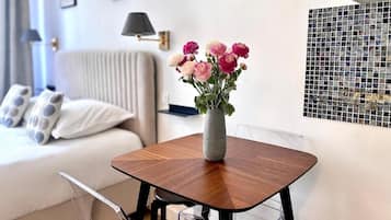 A modern living room with a wooden coffee table, a vase with flowers, a sofa, and a wall with a mosaic.