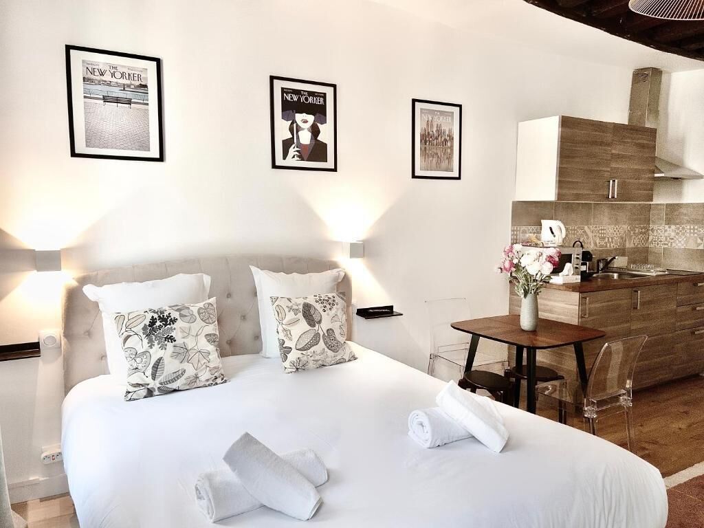 A hotel room with a bed, a small table, and a kitchenette.
