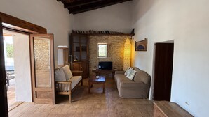Una sala de estar acogedora con pared de piedra, muebles de madera y televisor.