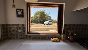 Una cocina con un amplio ventanal, una lámpara colgante e impermeable de azulejos.
