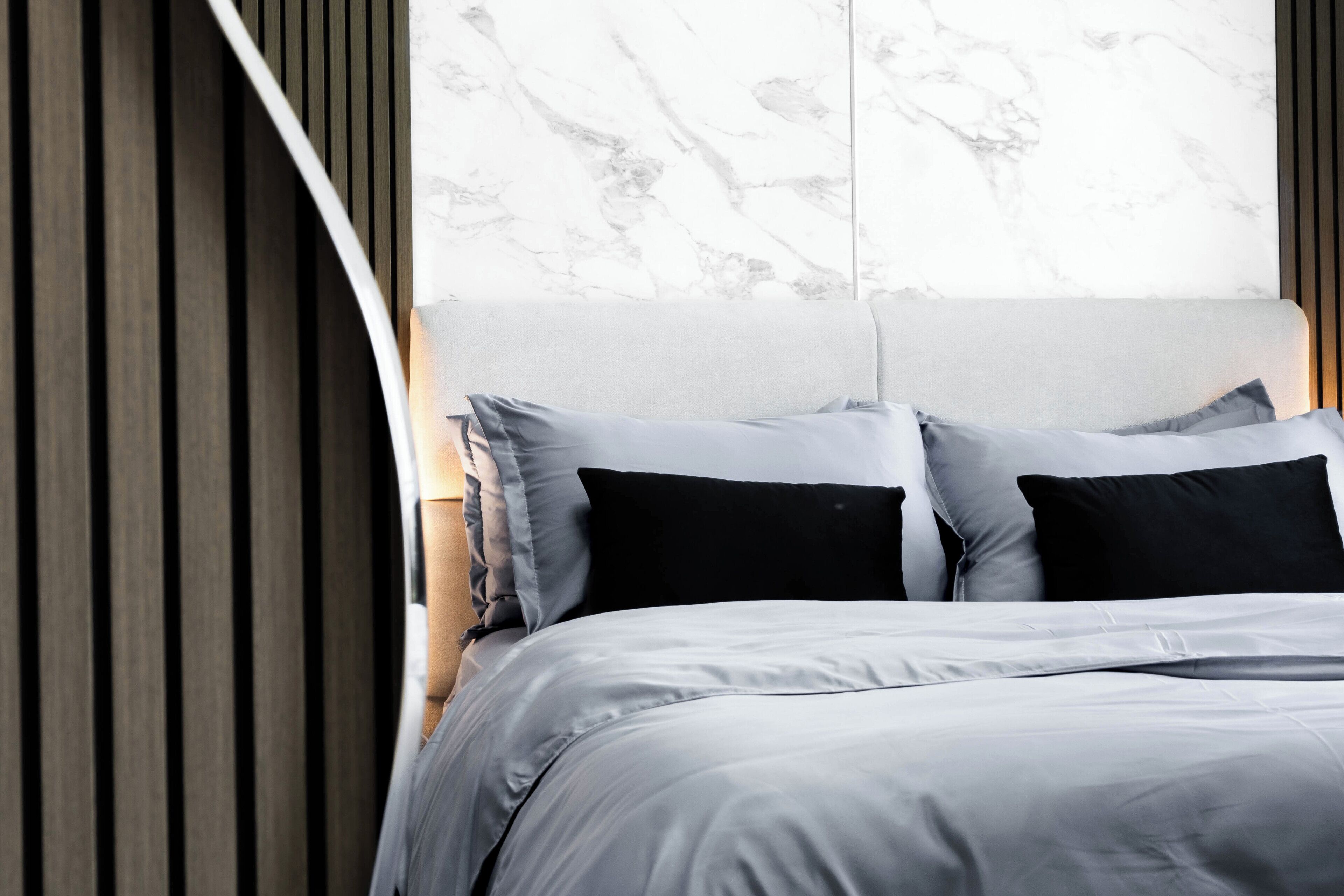 A modern bedroom with a bed, a marble headboard, and wooden paneling.