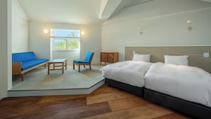 A bedroom with a large bed, a sofa, a chair, and a small table. There is a window with a view of greenery. - Nishi-Karuizawa Hotel atelier bla by LONGINGHOUSE (Miyota)