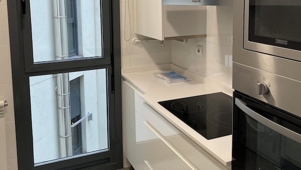 A modern kitchen with white cabinetry, a black stovetop, and a built-in oven.