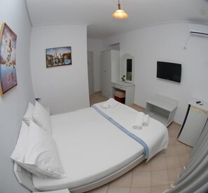Una camera da letto con un letto grande, una televisione, una scrivania e uno specchio.