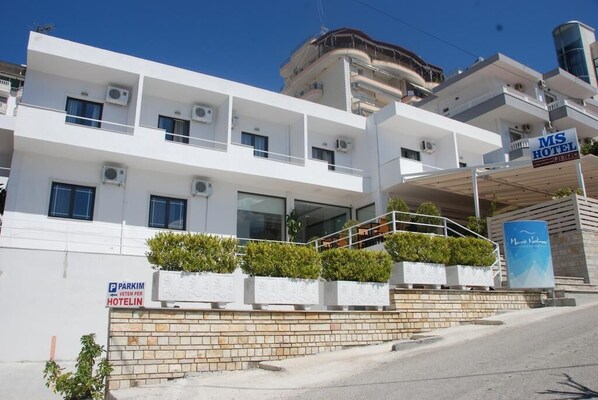 Un hotel moderno con diversi piani, condizionatori d'aria e un cartello con la scritta MS Hotel.