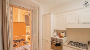 Una cocina moderna con armarios blancos, una estufa a gas y un pequeño comedor con mesa y sillas.