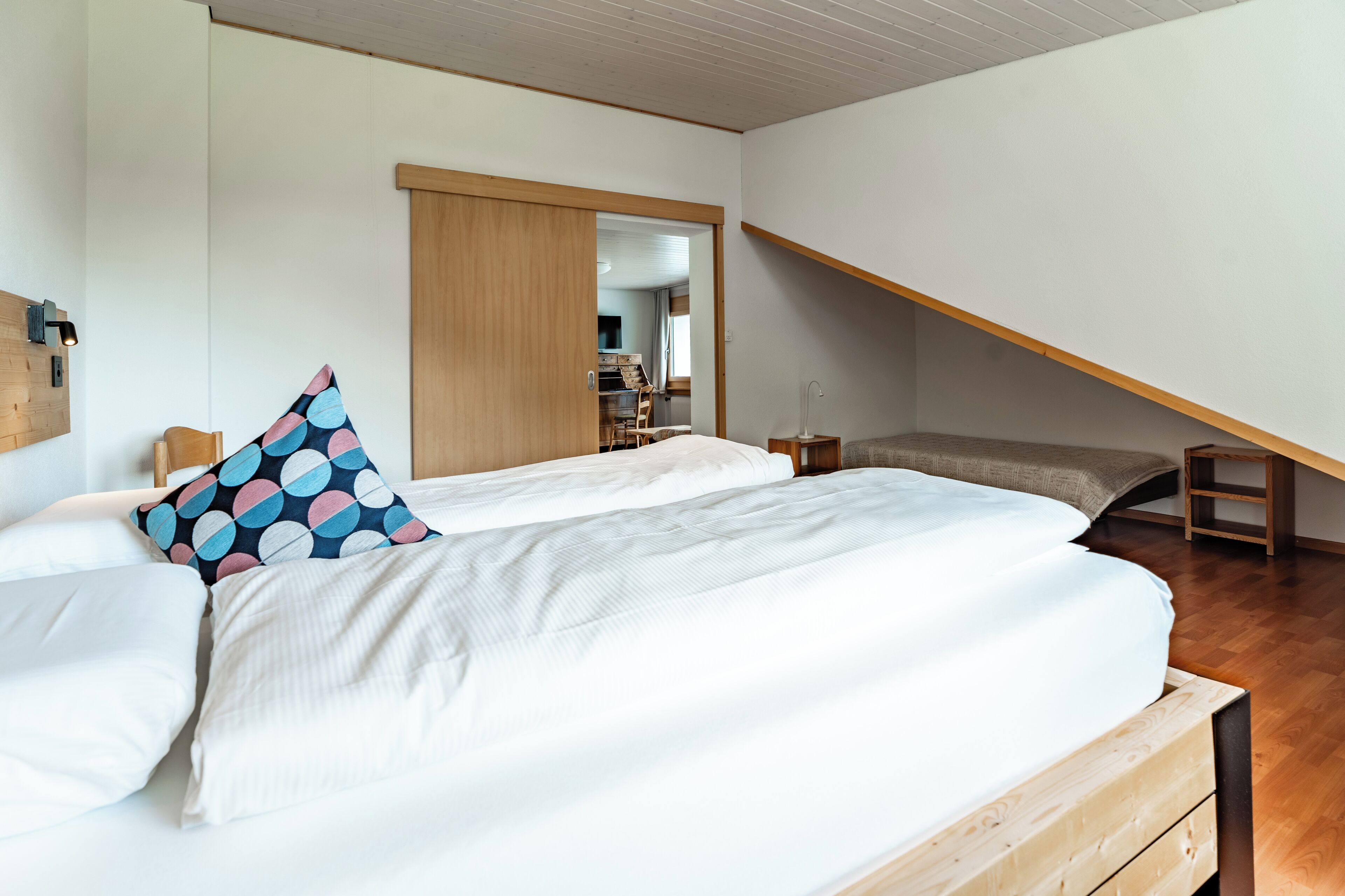 A modern bedroom with a large bed, a wooden bench, and a wardrobe.