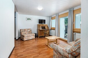A living room with a sofa, a wooden table, a TV, and a wooden cabinet.