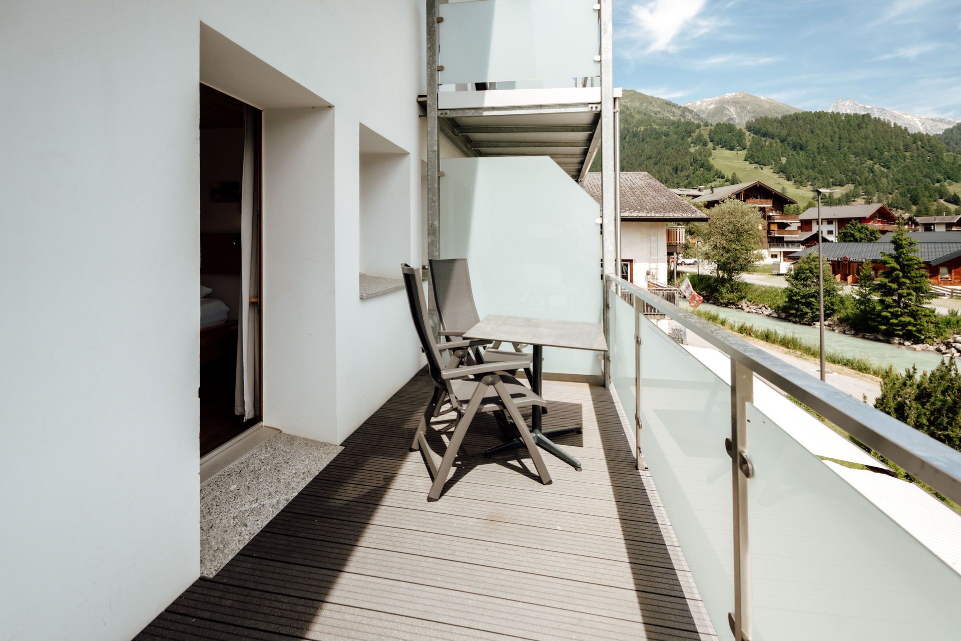A balcony with a wooden floor, a table, and two chairs.