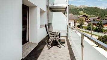 A balcony with a wooden floor, a table, and two chairs.