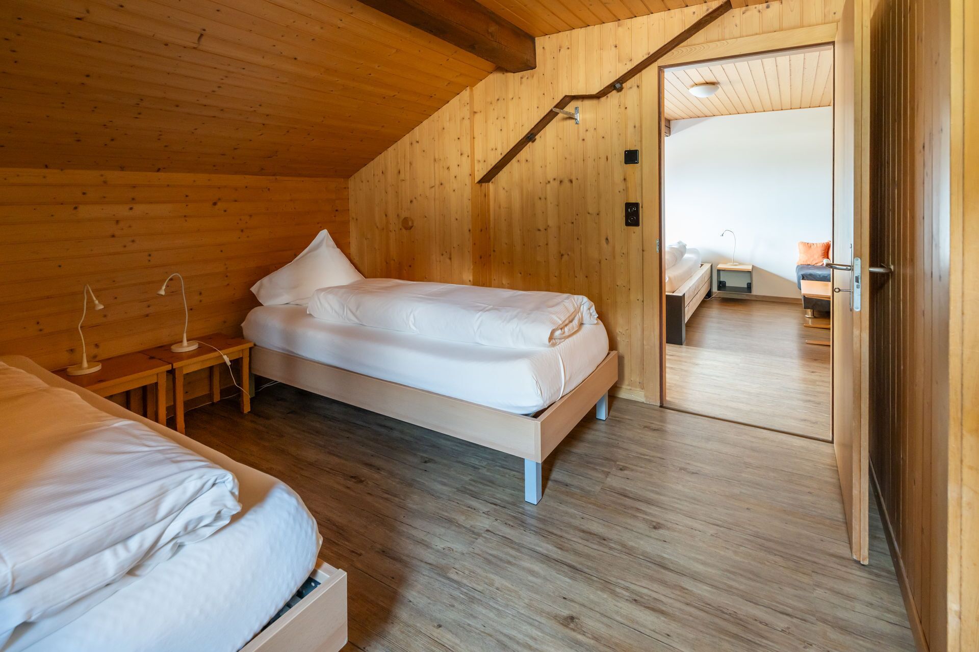Een houten slaapkamer met een enkel bed, een nachtkastje en een lamp.