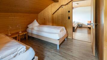 Een houten slaapkamer met een enkel bed, een nachtkastje en een lamp.