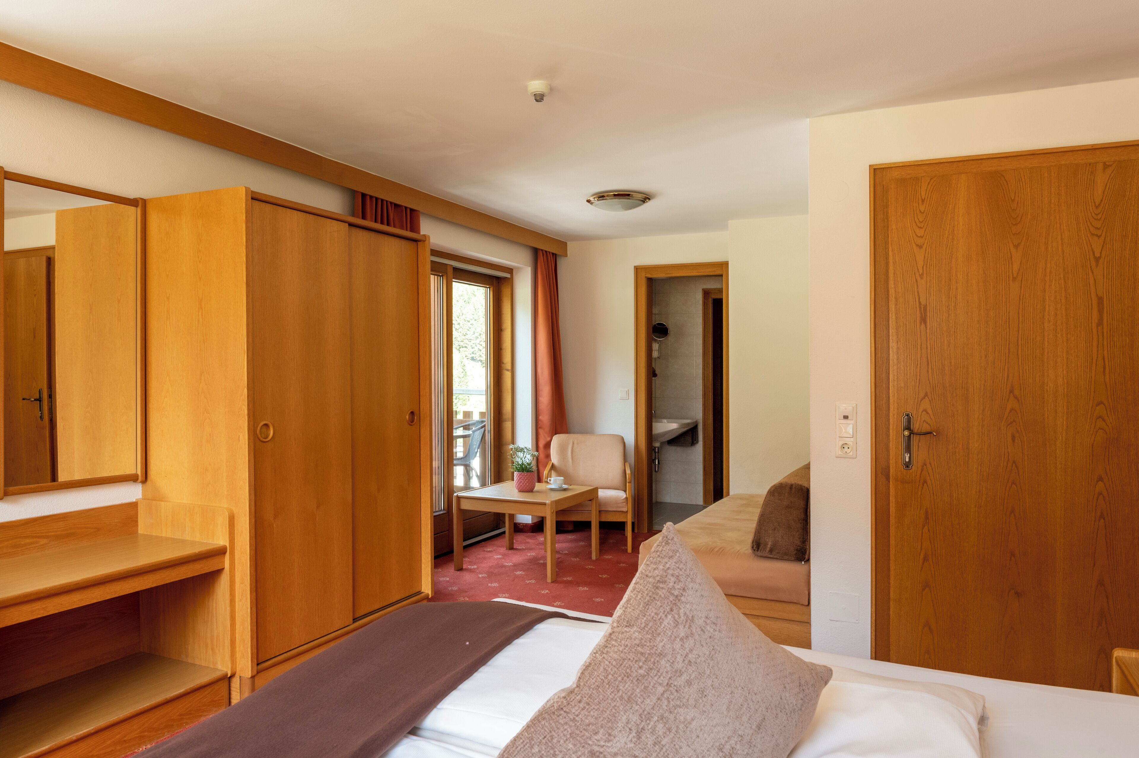 A hotel room with a bed, a desk, a chair, and a wardrobe.