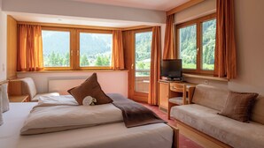 A hotel room with two beds, a TV, and a view of mountains. - Alpine B&B (Sankt Leonhard im Pitztal)