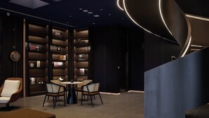 Un interior moderno con un elemento decorativo de luz curva, una mesa redonda con sillas y una estantería llena de objetos.
